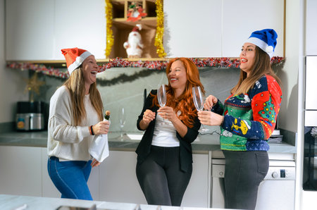 Three cheerful women wearing santa hats are enjoying christmas celebrations at home, making a toast with champagne and having funの写真素材