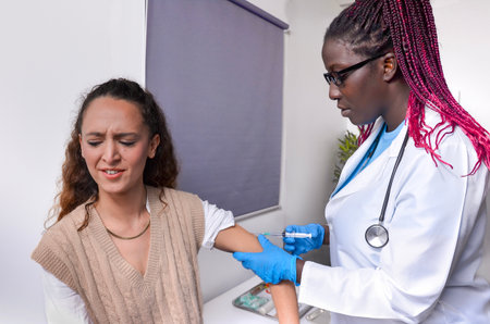 Female doctor giving a vaccine injection to a scared female patient in a medical clinic
