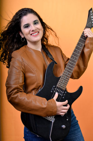 Female musician smiling and playing her electric guitar during a studio photo shoot