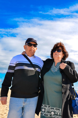 Happy retired couple walking on the beach on a sunny day, enjoying their free time togetherの写真素材