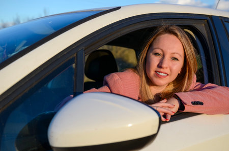 Smiling businesswoman leaning out of car window during road tripの写真素材
