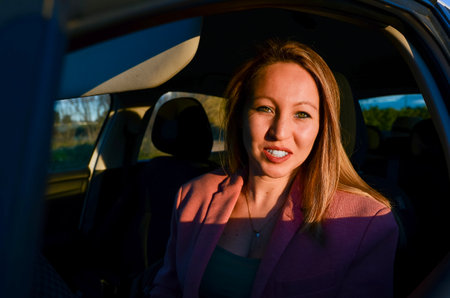 Young businesswoman smiling during a relaxing car trip at sunsetの写真素材