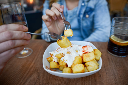 Couple enjoying traditional spanish tapas, patatas bravas with aioli, accompanied by vermouth, celebrating valentine's dayの写真素材