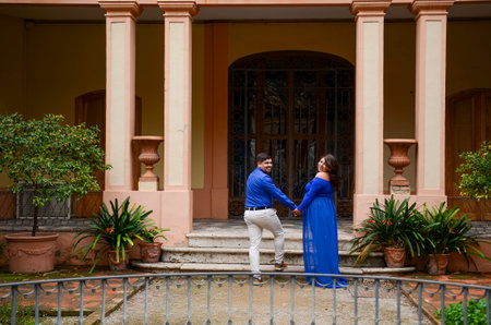 Future parents holding hands and walking away from the entrance of a building, looking back at the cameraの写真素材