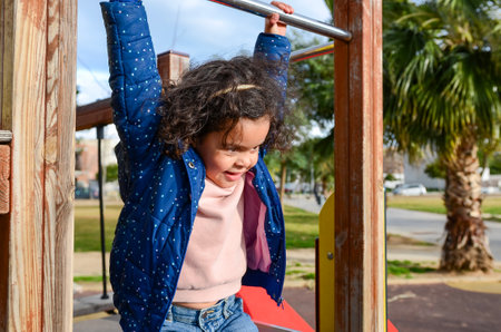Young girl hanging from monkey bars, enjoying playtime at the playgroundの写真素材