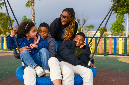Mother and children enjoying a day at the playground, swinging and laughing together