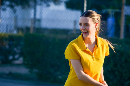 Female tennis player smiling while playing tennis on a sunny dayの写真素材