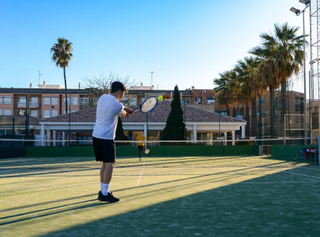 Young tennis player serving the ball during a match on a sunny dayの写真素材