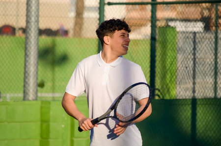 Young athlete playing tennis, holding racket and following ball with his eyes, enjoying sport activity on courtの写真素材
