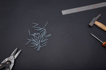 Flat lay of construction tools including hammer, screws, ruler, screwdriver and pliers arranged on...