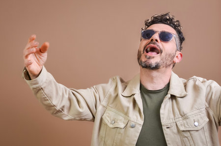 Male singer wearing sunglasses performing with passion and energy on stage, singing with emotionの写真素材
