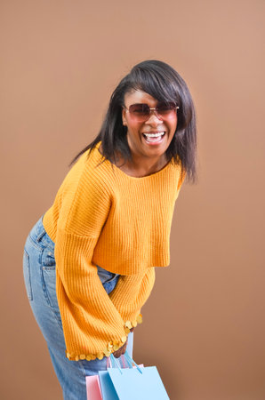 Studio shot of a cheerful customer laughing while carrying colorful shopping bagsの写真素材