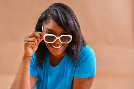 Studio portrait of a cheerful woman lowering her sunglasses and smilingの写真素材