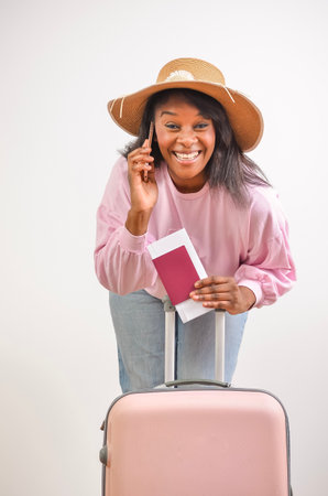 Tourist smiling and talking on the phone while holding passport and tickets, ready for vacationの写真素材