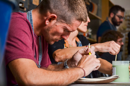 Potters refining a clay plate in a ceramics workshop, using tools for modelingの写真素材