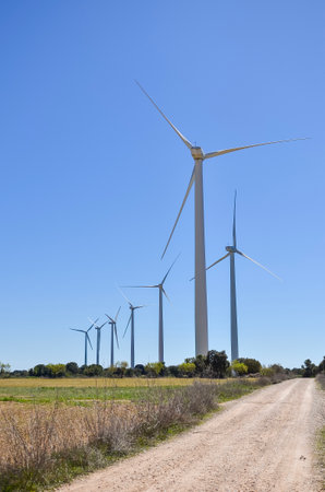 Wind turbines stand tall in a field, generating clean energy and representing a sustainable approach to power generationの写真素材