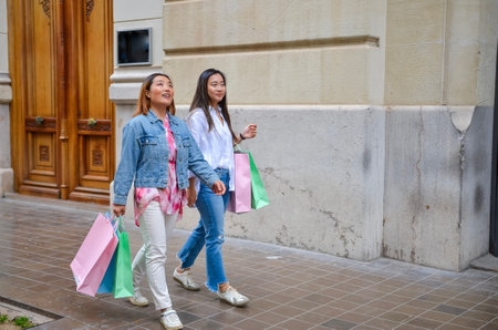 Two young women walking on the sidewalk, carrying shopping bags after a shopping spreeの写真素材