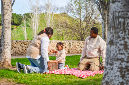 Parents sharing joyful moments with their child during a picnic in a park, celebrating family bonds and creating lasting memoriesの写真素材