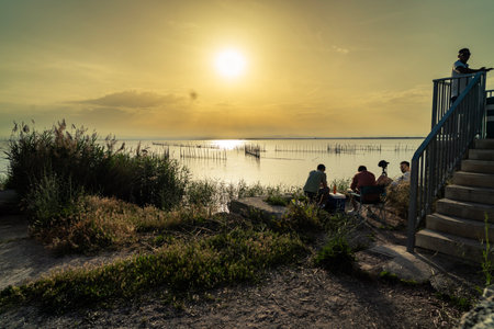 People enjoying a peaceful sunset by the tranquil lakeの写真素材