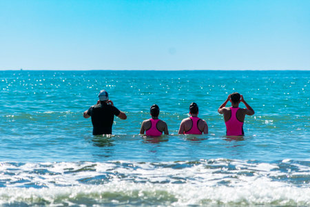 Athletes wearing wetsuits are preparing to start an open water swimming race in the ocean during...