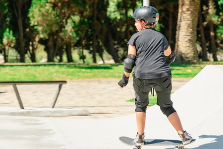 Young skateboarder wearing helmet and protective gear practicing in a skate parkの写真素材