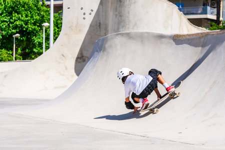 Young boy skateboarding in a concrete skatepark, practicing tricks and enjoying the urban environmentの写真素材
