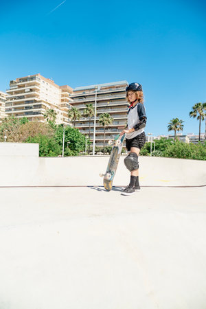 Young skater holding his skateboard in a skatepark wearing safety equipmentの写真素材