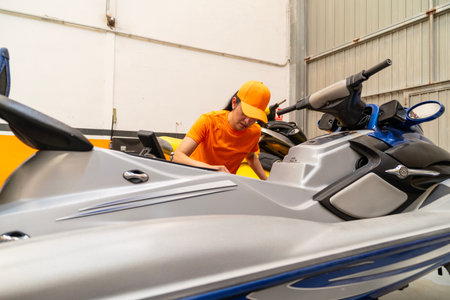 Female mechanic examining a jet ski in a workshop, performing maintenance and repairsの写真素材