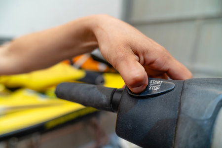 Close-up of hand activating start button on handlebar of machinery, suggesting beginning of...