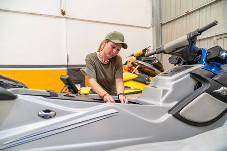 Female mechanic working on a jet ski engine in a repair shopの写真素材