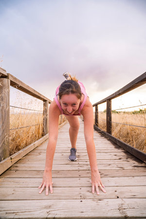 Fit woman stretching her legs on a wooden walkway in natureの写真素材