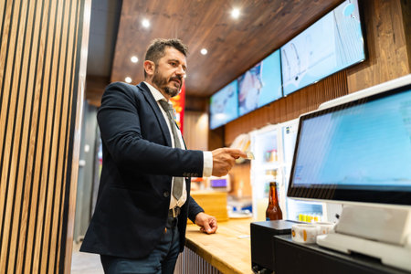 Confident man in suit using card for cashless payment at a digital counterの写真素材