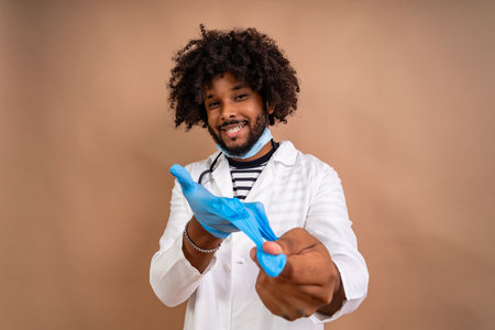 Smiling young male doctor putting on a protective blue gloveの写真素材