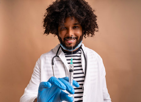 Smiling man in lab coat holding syringe with needle, ready for immunizationの写真素材
