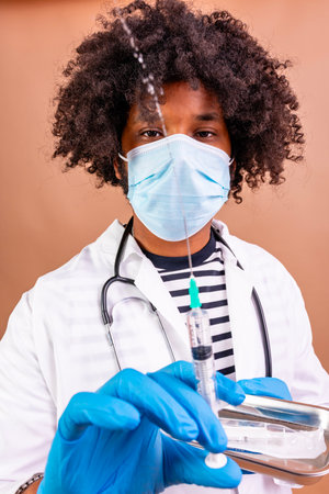 Medical worker wearing mask and gloves preparing a syringe with liquidの写真素材