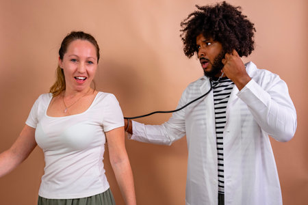 Doctor reacting with shock while listening to patient with stethoscope during checkupの写真素材