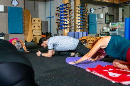 Participants engaging in a stretching exercise on yoga mats in a gym setting