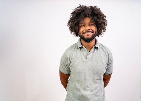 Young black man smiling at camera, hands behind back on a white backgroundの写真素材