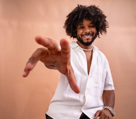 Young man smiling and extending a welcoming hand directly towards the viewer
