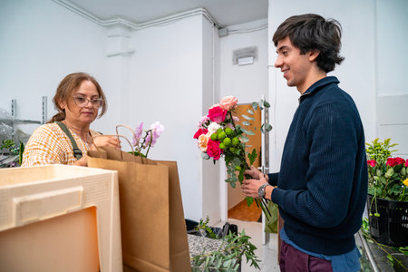 Florist serving male customer handling bouquet of fresh flowers in a flower shop