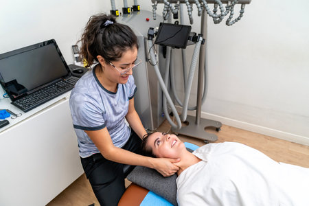 Physiotherapist performing manual physical therapy on a woman patient's neck in a clinic