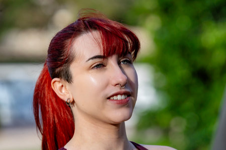 Young woman with dyed red hair expressing individuality outdoorsの写真素材