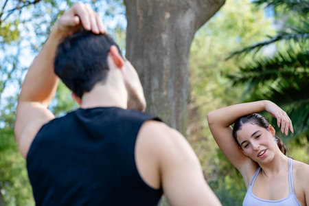 Couple performing neck stretches together, preparing for exercise in a park