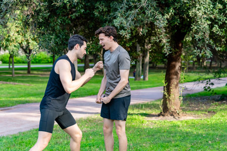 Two young men engaging in a playful fist fight in a vibrant park