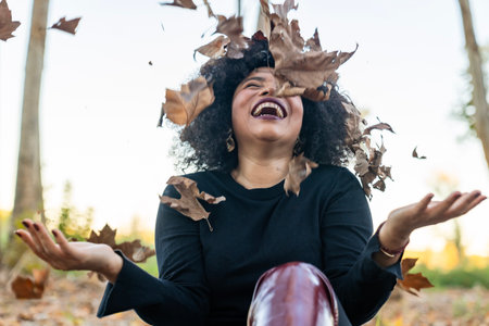 Joyful african american woman laughing while enjoying autumn foliage outdoorsの写真素材