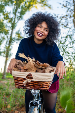 Smiling woman with curly hair enjoying fall bicycle ride in natureの写真素材