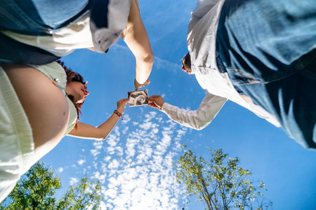 Expectant couple holding sonogram picture against a clear blue sky, celebrating new lifeの写真素材