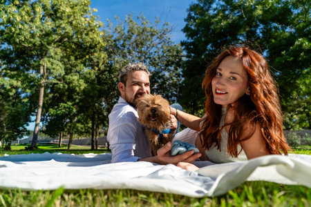 Smiling family with pet dog relaxing on a blanket outdoorsの写真素材