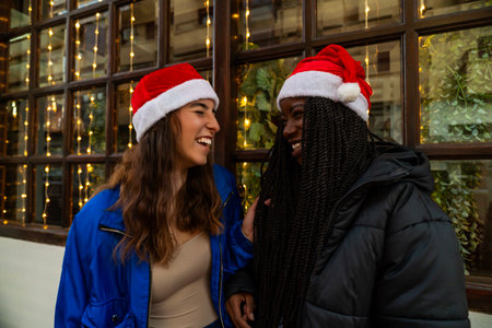 Young diverse women smiling and enjoying a festive moment with christmas lightsの写真素材