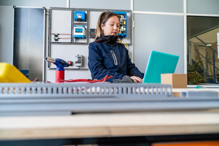 Woman engineer monitoring solar power control panel with laptop in a workshop setting
